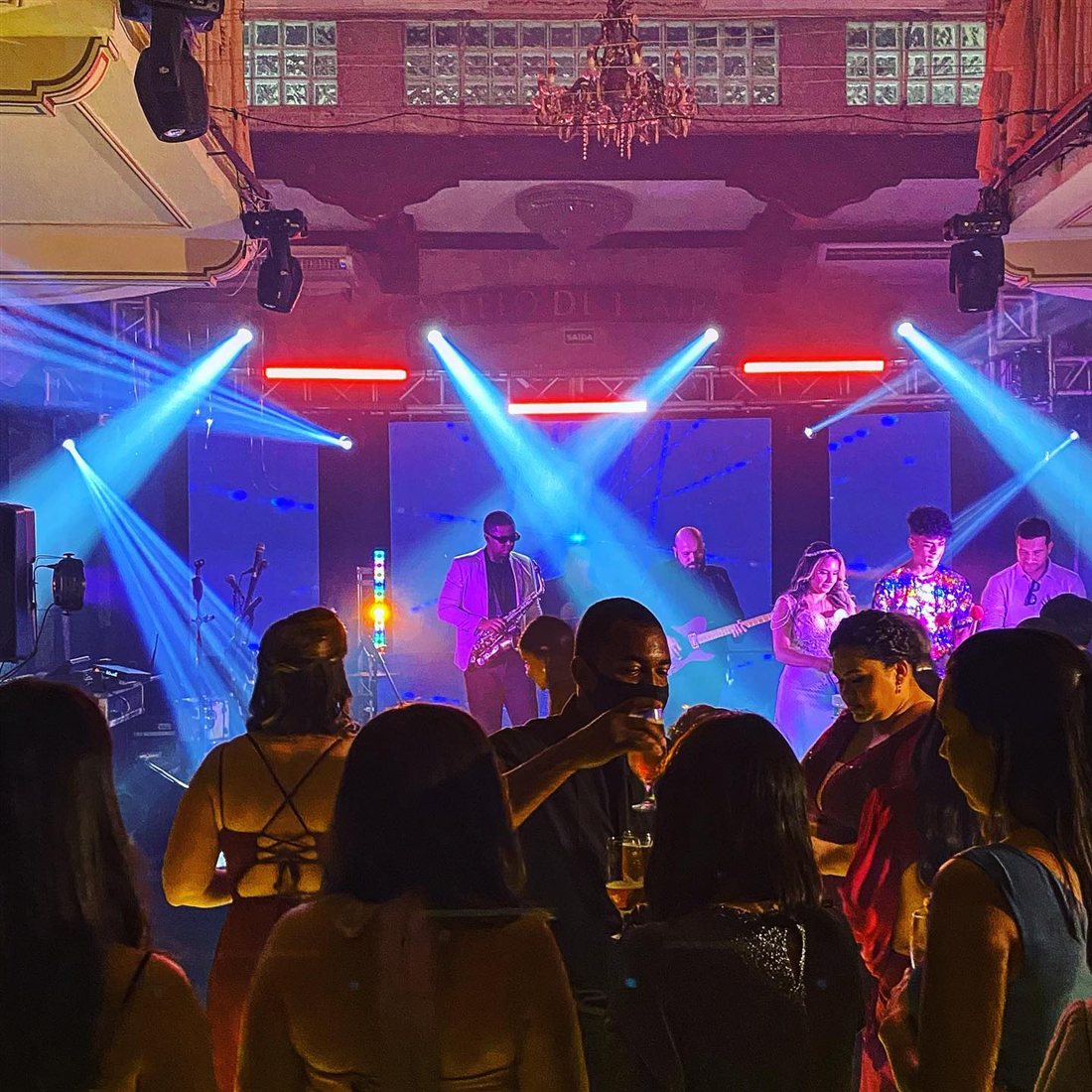 Banda ao vivo com iluminação de moving heads cruzados operada pela MPC