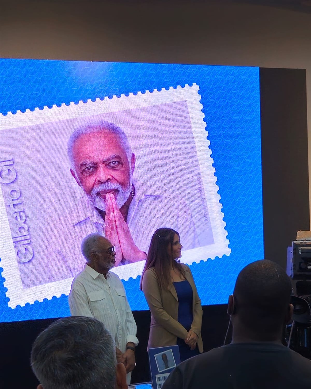 Painel de LED em evento com os Correios, exibindo arte de selo comemorativo